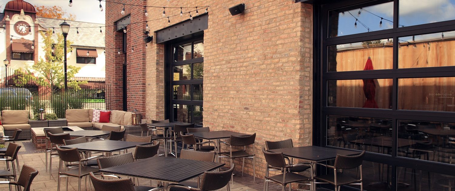 This image is Mickey Finn's outdoor patio, design elements include exposed steel frame and ten-foot garage style overhead doors that open to the dining room.