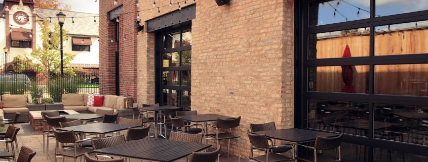 This image is Mickey Finn's outdoor patio, design elements include exposed steel frame and ten-foot garage style overhead doors that open to the dining room.